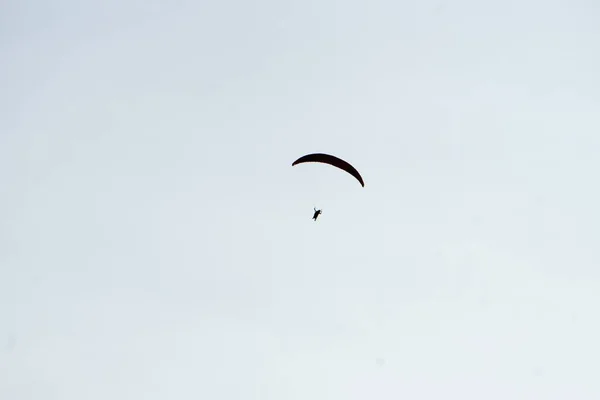 Close de um homem pulando de paraquedas perto do solo com um