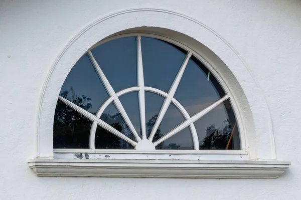 Крупный План Полукруглого Окна Рисунком Солнечной Вспышки Белой Стене Дома — стоковое фото