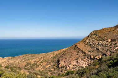 Önünde bir uçurum olan deniz ve mavi gökyüzü manzarası