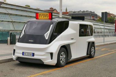 Kaldırımın kenarına park edilmiş beyaz bir ETIOCA tam otomatik minivan taksisi manzarası.