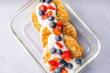 Yoğurt ve böğürtlenlerle kaplı sağlıklı krep manzarası.