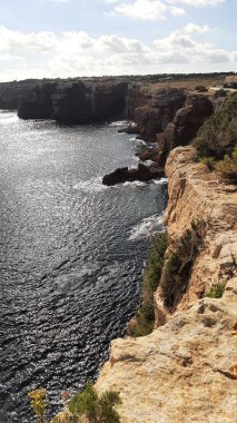 Formentera sahilindeki Punta Prima uçurumlarının mavi gökyüzü, dikey çekim