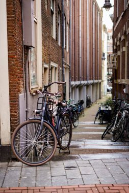 Amsterdam, Hollanda 'daki binaların duvarlarına eğilmiş bisikletlerin dikey bir görüntüsü