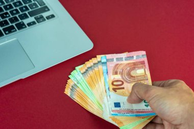 Avro banknotlarını dizüstü bilgisayara yakın tutan beyaz eller