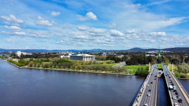 Parkın yakınındaki otoyollara ve mavi bulutlu gökyüzünün altındaki göle kuş bakışı bir bakış.