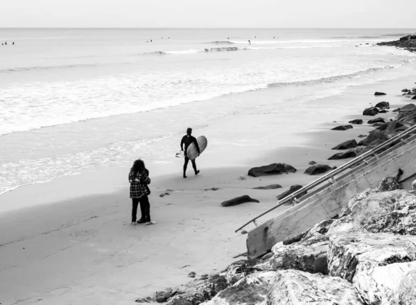 一对夫妇和一个冲浪运动员在海滩上拍的一张灰白色的照片 — 图库照片