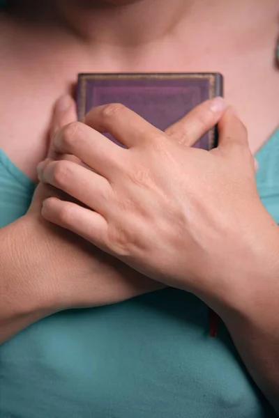 Ett Vertikalt Skott Händer Som Håller Liten Bok Nära Bröstet — Stockfoto