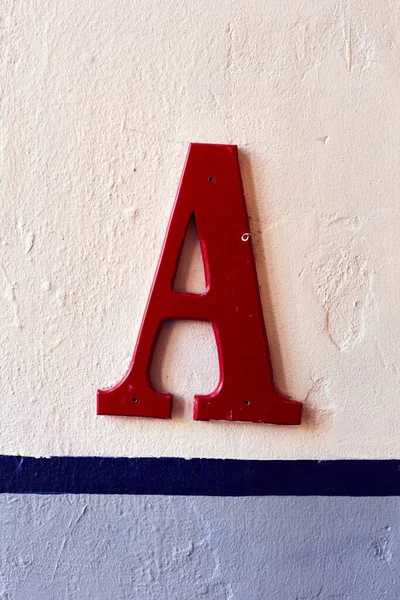 Egy Függőleges Felvétel Egy Piros Színű Nagybetűről Falon — Stock Fotó