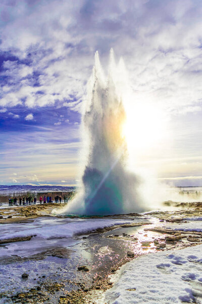 A vertical shot of a group of people near a Gaisir under the blue cloudy sky