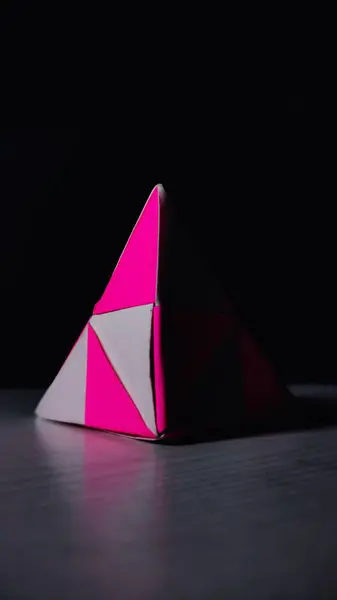 Colpo Verticale Una Piramide Origami Rosa Bianco Una Superficie Nera — Foto Stock