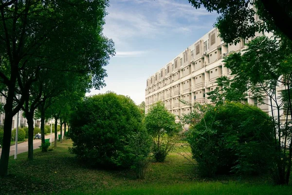 A beautiful view of an apartment building from a garden with green trees
