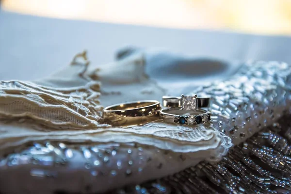 背景をぼかしたガラスビーズで装飾されたクリーム生地の上に結婚指輪 — ストック写真