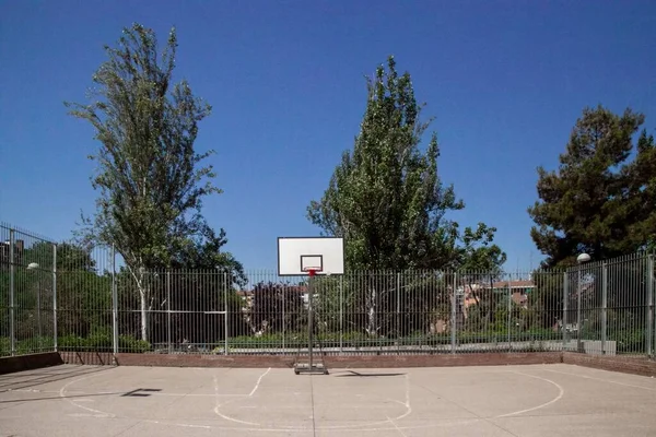 屋外のフェンスで囲まれたバスケットボールコート 裏庭で 晴れた日に緑の木々に囲まれて — ストック写真