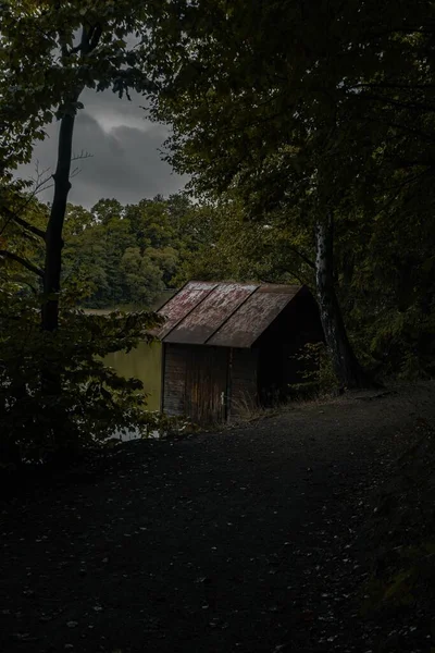 森の中の湖の岸にある古い木造の家の垂直ショット — ストック写真