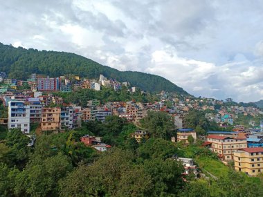 Arka planda dağlar olan bir kasaba ve doğa manzarası.