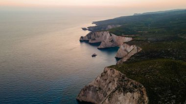 Resimli bir Yunan adasının insansız hava aracı görüntüsü ve manzaralı bir deniz manzarası.