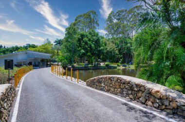 Güneşli bir günde, Queensland, Avustralya 'da, güneşli bir günde, yeşil ağaçların yansımasının olduğu göl kenarında bir yol.