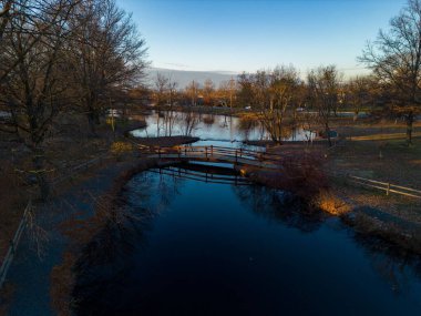 Güneşin doğuşunda gölü olan sessiz bir parkın üzerinde bir hava manzarası.