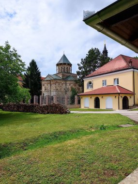 Arka planda bir bina ve kilise olan bir çayır parkı.