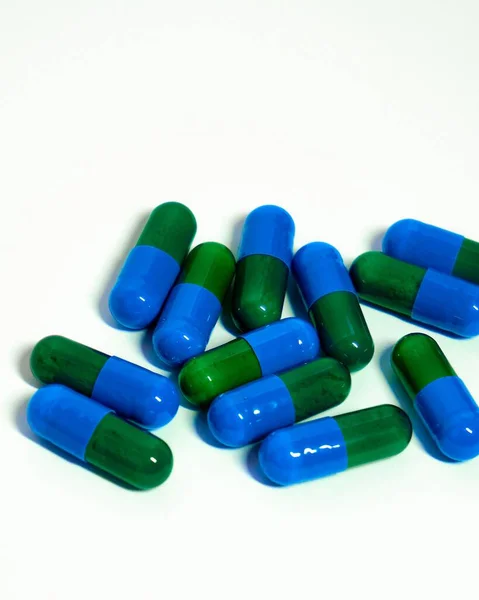 白色背景上的绿色和蓝色药丸的垂直特写照片 — 图库照片