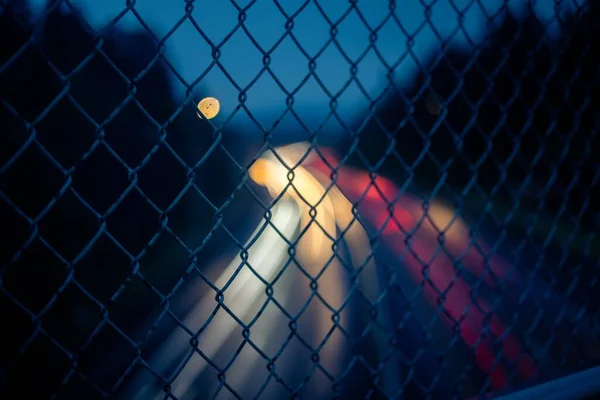 Closeup Shot Metal Fence Grid Blurred Light Trails Background — Stock Photo, Image