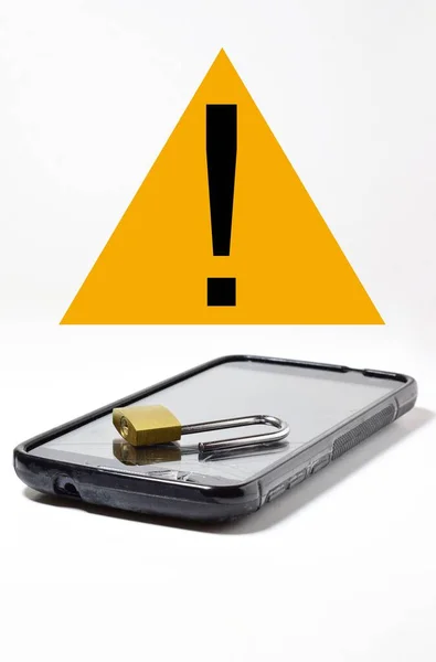 stock image A steel lock on a smartphone with yellow caution sign in the background-concept of security and internet