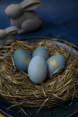 Paskalya kutlaması için bir yuva gibi dekore edilmiş tabakta mavi renkli yumurtaların yakın çekimi.