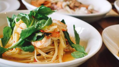 Üzerinde peynir ve ıspanak olan beyaz bir tabakta yakın plan makarna.