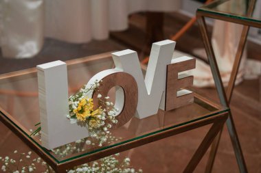 Cam bir masanın üzerinde ağaçtan yapılmış, çiçekli bir aşk kelimesi.