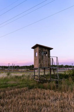 Gün batımında Avusturya 'da bir tarladaki tahta avcı kulesinin dikey görüntüsü.