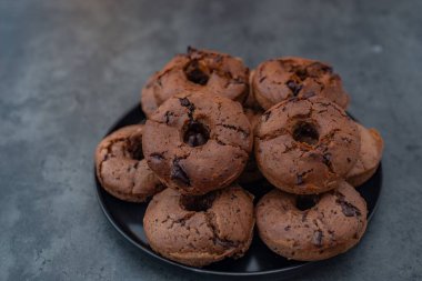 Gri arka planda siyah tabakta lezzetli çikolatalı çörekler.