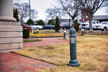 Çimenleri ve açık hava ışıkları olan taştan bir avlu.