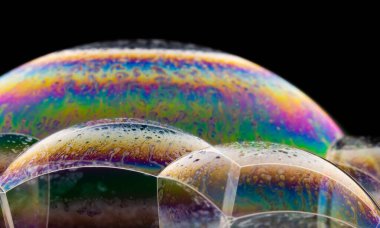 Siyah arkaplanda renkli sabun köpüklerinin yakın plan çekimi.