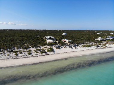Mavi suyu, kumu ve güzel gökyüzü olan bir sahil görüntüsü.