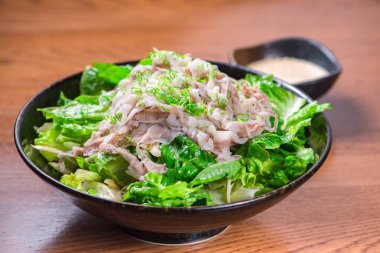 Salatanın yakın plan çekimi. İçinde salata ve et var.