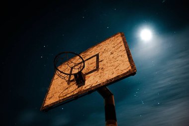 Gece yıldızlı gökyüzüne karşı basketbol potasının alçak açılı görüntüsü