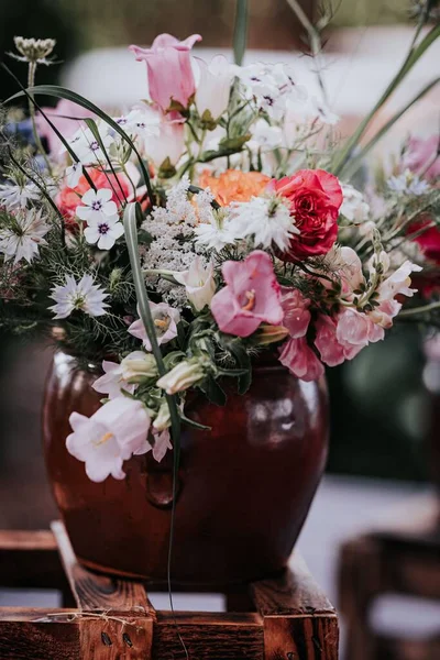 花瓶里有一束五颜六色的花和叶子 站在一个木制的调色板上 — 图库照片