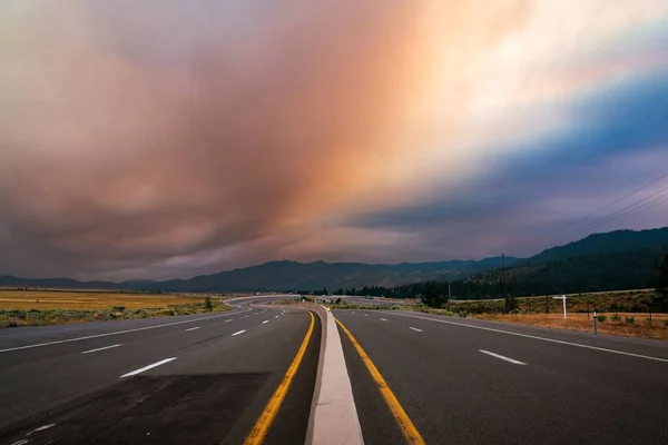 野火の雲の下でネバダ州のウォショー渓谷に向かう空の道路 — ストック写真