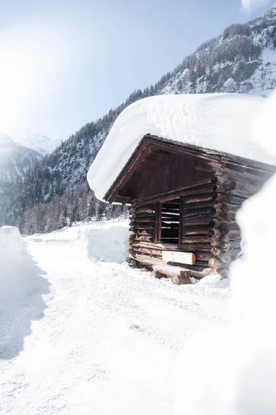 阳光明媚的日子里 一座被雪覆盖着群山的木头房子的立面照片 — 图库照片