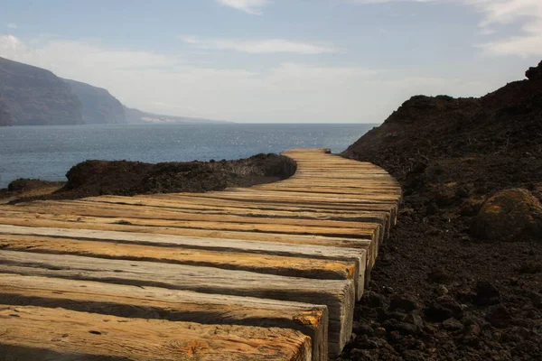 stock image A low-angle shot of a wooden path leading to the calm sea water to a beautiful view