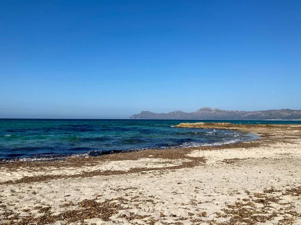 stock image A closeup shot of Cala Formentor beach, a bright blue sea and mountains in the distance