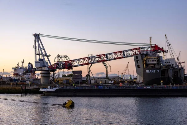 工业内陆航运五彩斑斓的起重机在日落蓝色的时间停泊在港口 工程重型机械结构和物流概念 — 图库照片