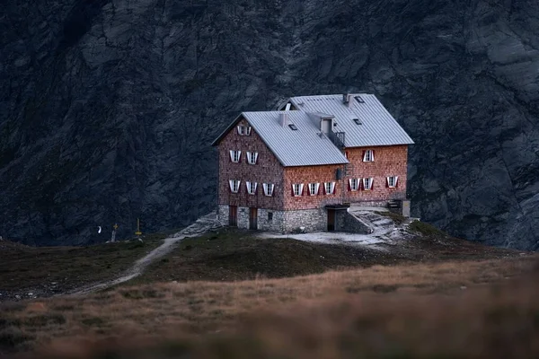 Arkasında Kayalar Olan Bir Dağın Tepesinde Turuncu Bir Bina — Stok fotoğraf