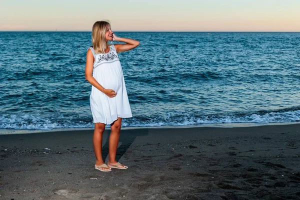 一个西班牙裔孕妇在日落时在海滩上 — 图库照片