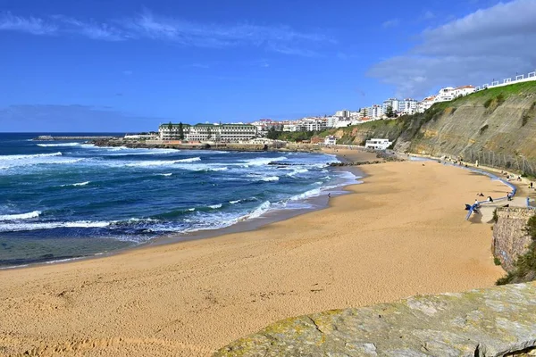 Güneşli bir günde güneşli bir günde Ericeira, Portekiz 'de kumlu bir sahil manzarası ve uzak binalar.