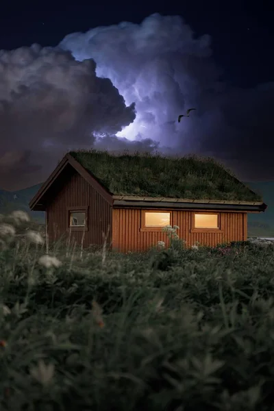A vertical shot of a stormy purple thunder sky over a wooden cabin