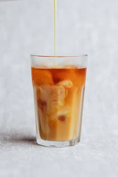 バニラ豆乳を氷でコーヒー冷たい醸造酒に注ぐ垂直 ストック写真