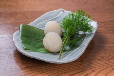 Tabaktaki muz yaprağının üzerinde çiğ deniz tarağı yakın plan çekimi.