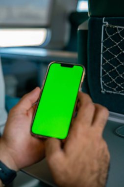 Kimliği belirsiz adam elinde yeşil ekranlı bir akıllı telefon tutuyor.,