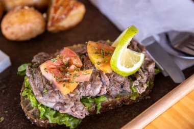 Bir parça bifteğin ve bir dilim ekmeğin üstüne konmuş marulun yakın plan çekimi.